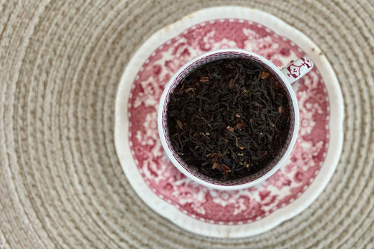 Teacup full of black tea with cacao nib