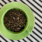 Green teacup full of black tea, mint, and chocolate