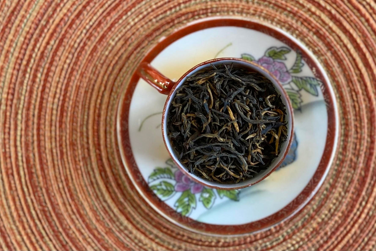 teacup full of black tea with gold tips