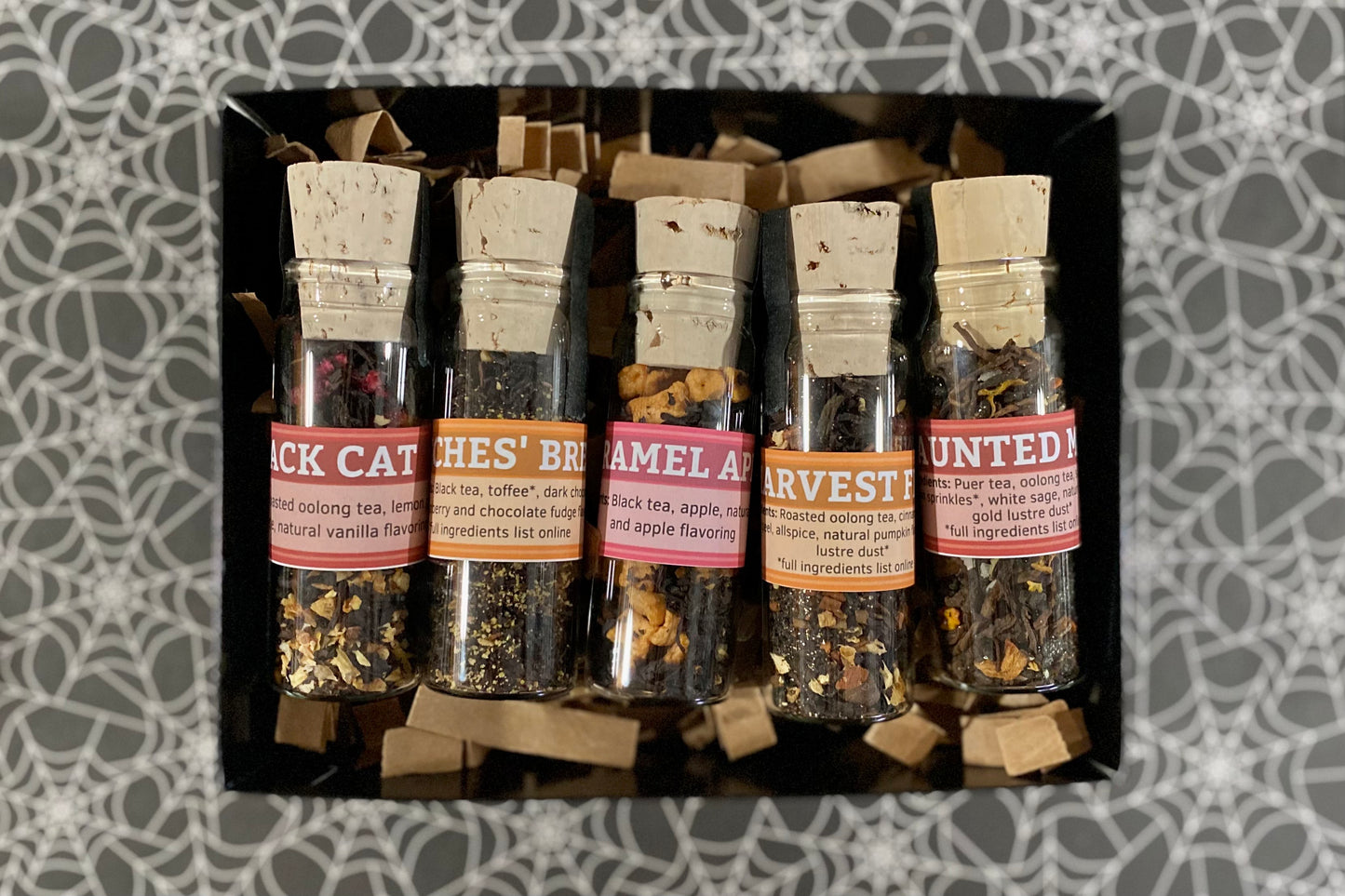 Set of tea samples in small glass jars with labels on a patterned background