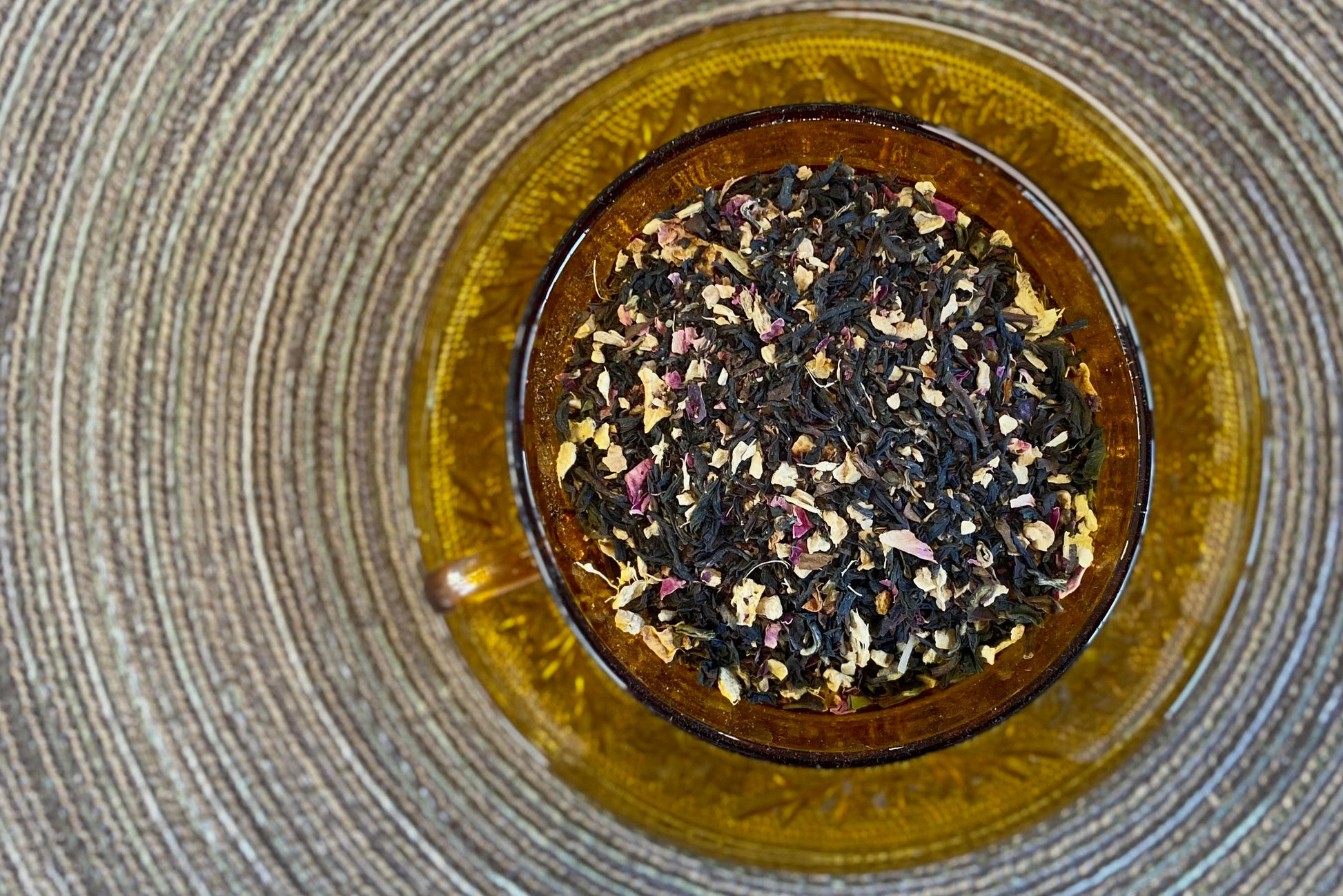 teacup full of black tea with orange and pink botanicals
