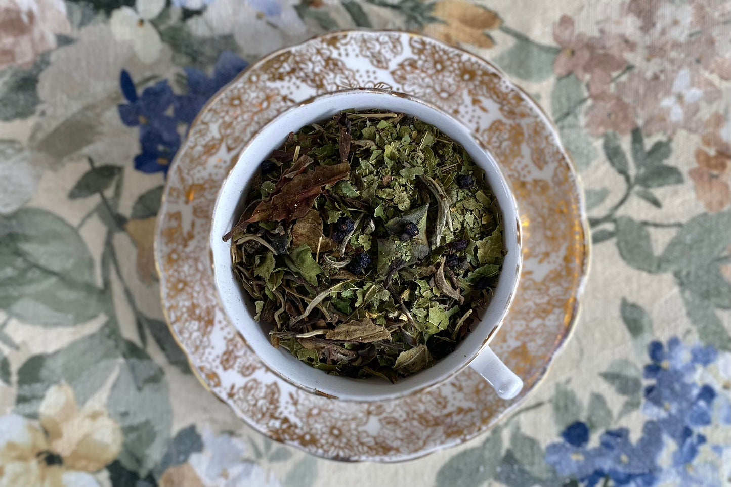 teacup full of gold glittery white tea with mulberry leaf