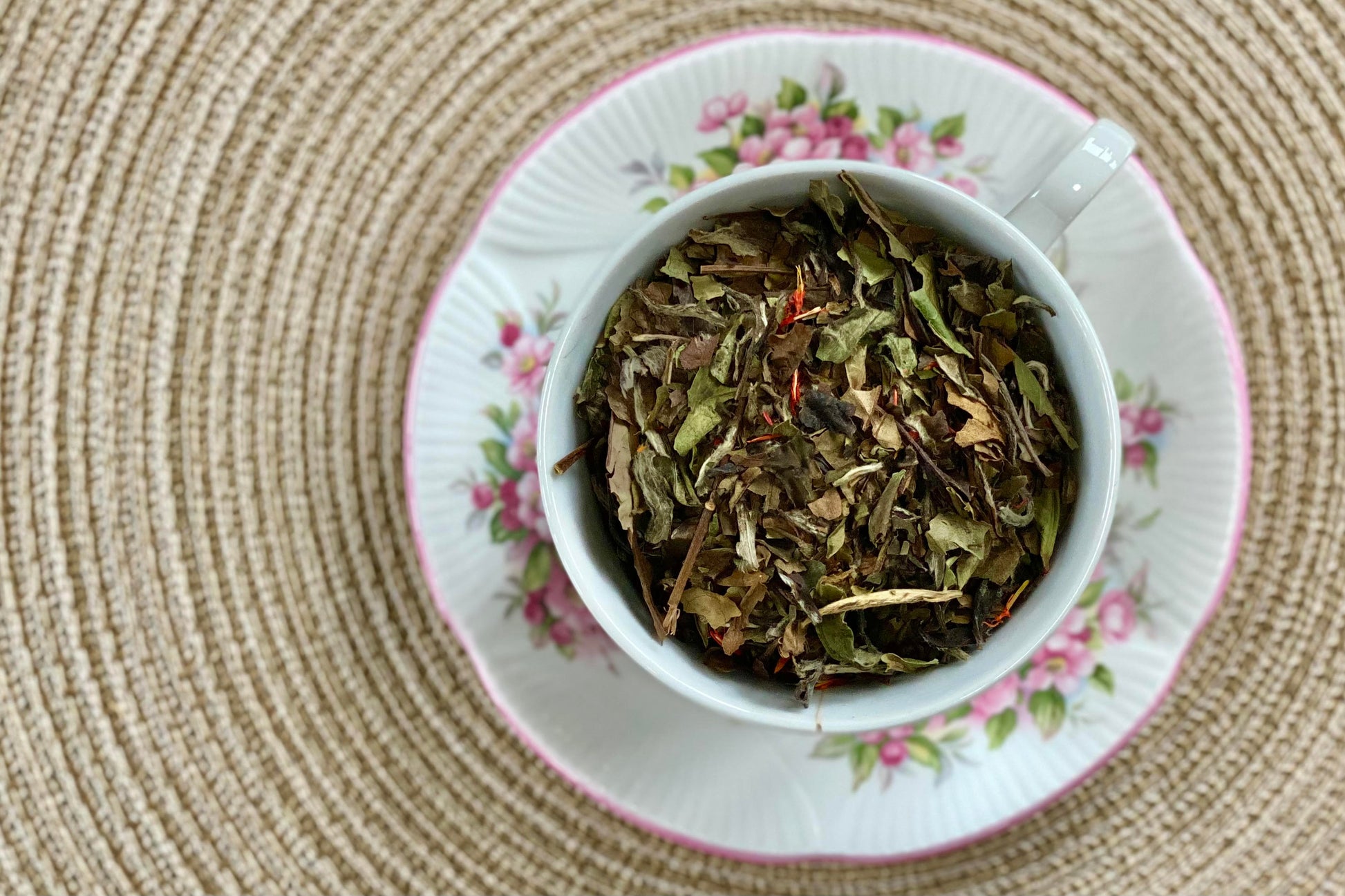 Teacup full of white tea leaf with safflower petals