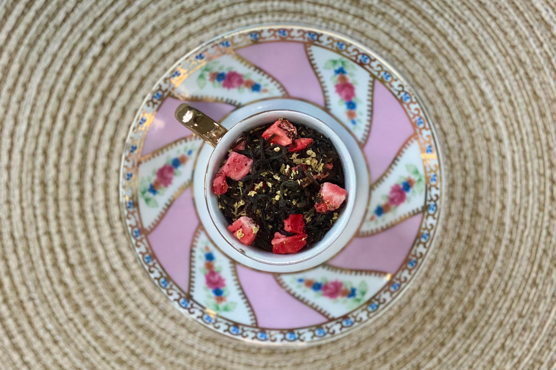 teacup full of black tea with strawberries