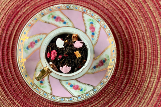 teacup full of black tea, teapot sprinkles, glitter and raspberries