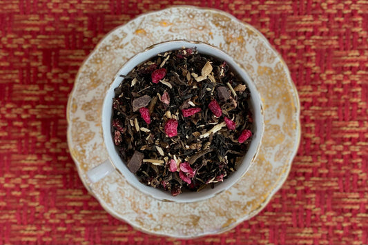 teacup full of dark tea, pomegranate seeds, chicory root and chocolate