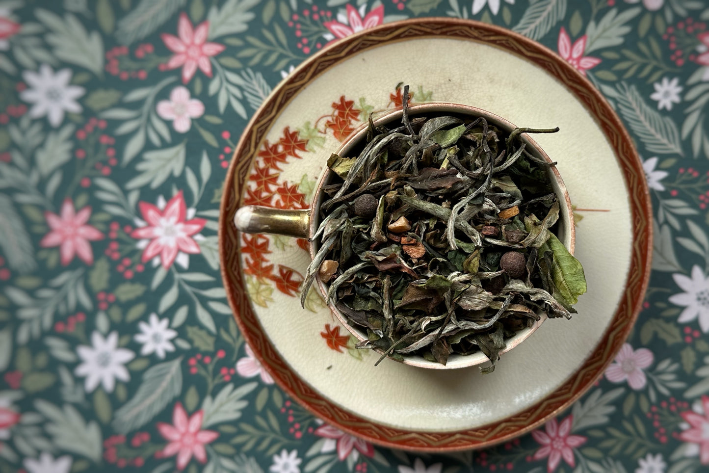 Tea leaves in a teacup on a floral-patterned fabric background