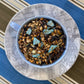 Teacup full of roasted barley, glittery aloe pieces and tea leaf