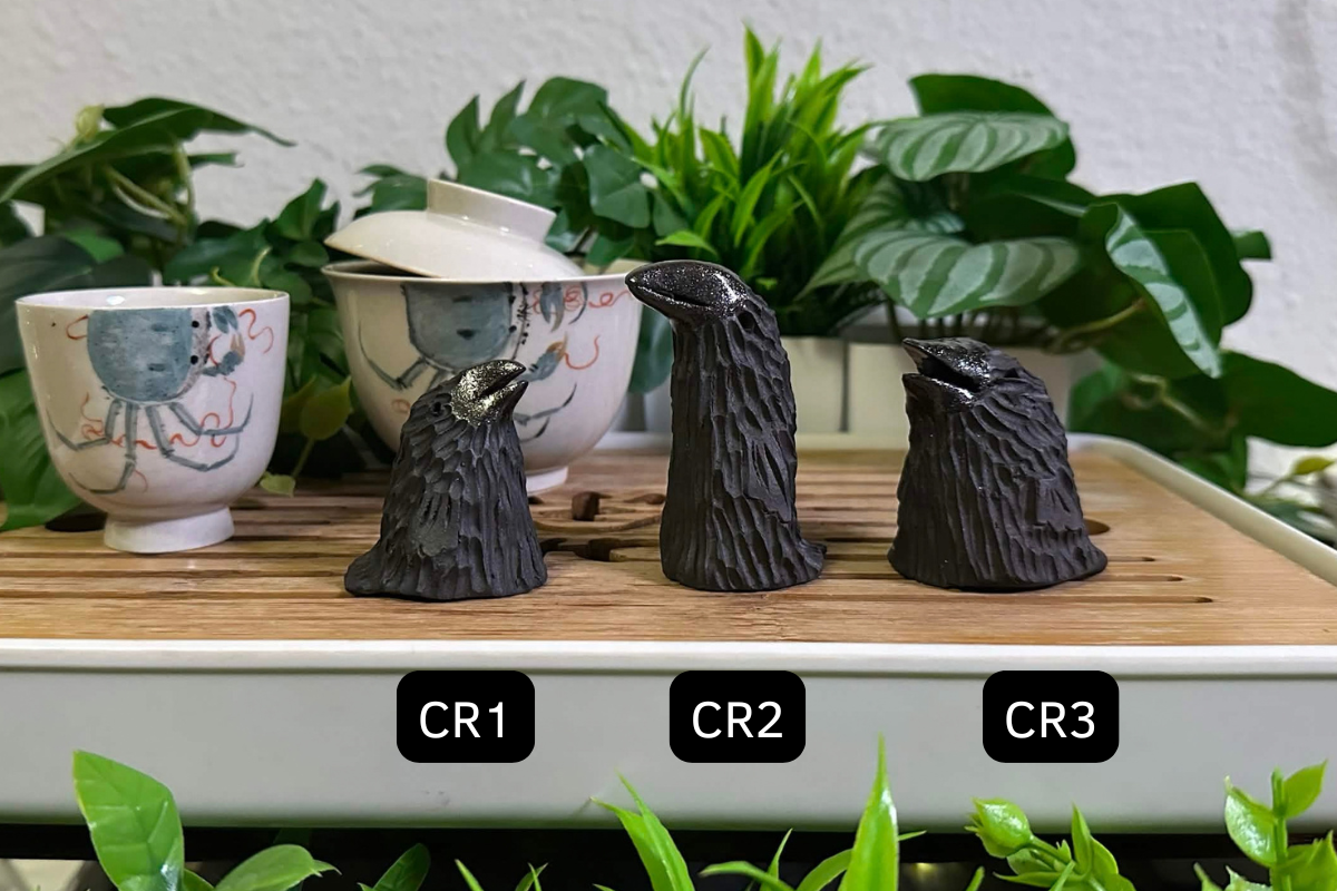 Three crow tea pets on a gongfu tray. All have matte black bodies and glittery glossy black beaks. CR1 is short and squat, CR2 is tall and thin, and CR3 is quite round.