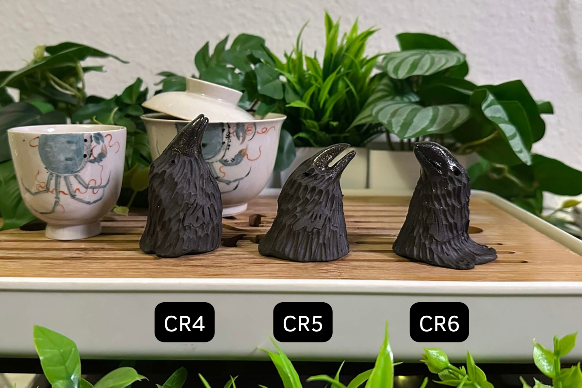 Three crow tea pets on a gongfu tray labeled CR4-CR6. All three are short and have matte black bodies and glittery glossy black beaks.