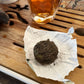 Tea cake on a piece of paper with a glass of tea in the background on a wooden surface.