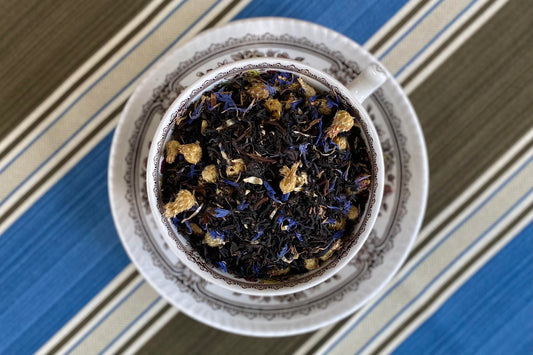 teacup full of black tea with blue cornflower