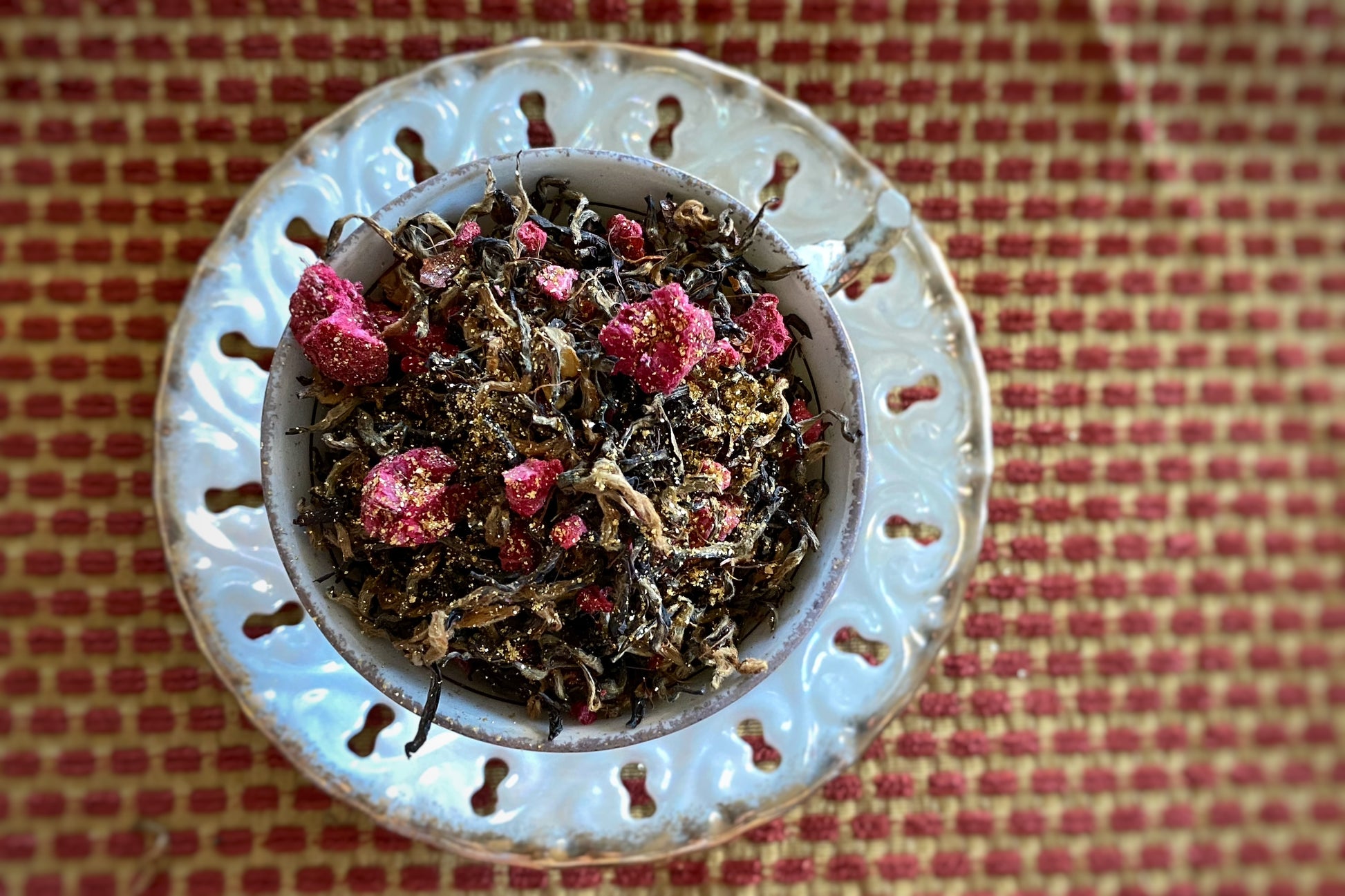 Teacup full of gold glitter black tea with raspberry