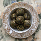 A white and gold teacup full of pressed white tea balls with jasmine flowers