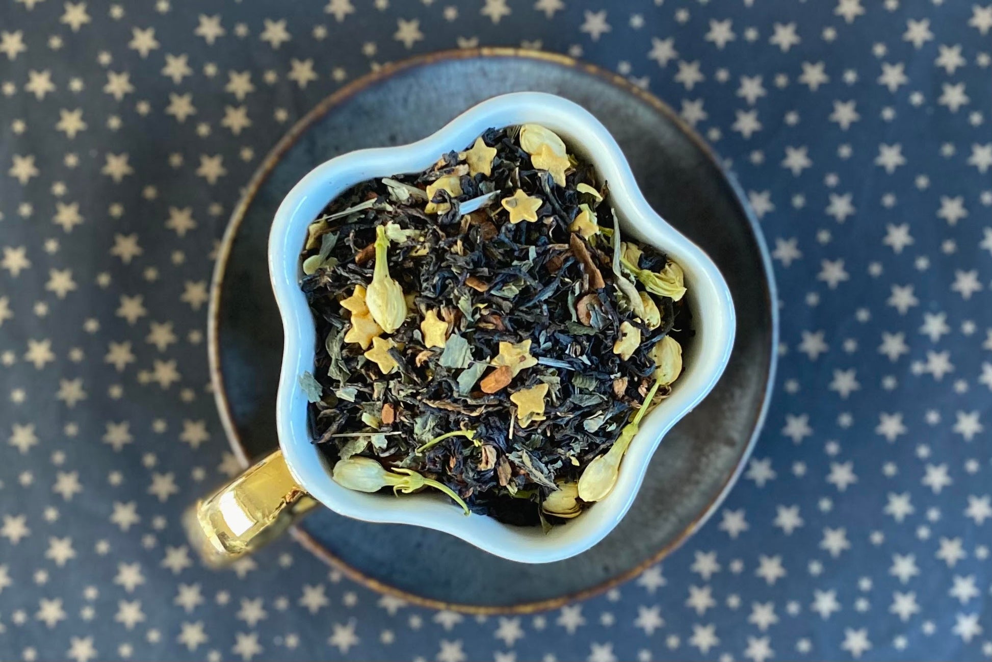 star shaped teacup full of tea leaf, star sprinkles, and jasmine flowers