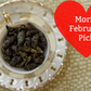Tea leaves in a white teacup with a red heart-shaped label reading 'Mori's February Pick!' on a textured beige background.