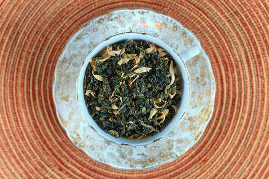 teacup full of rolled oolong leaf with orange blossoms and gold glitter