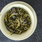 teacup full of white tea with berries and blue flowers