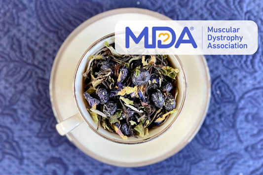 teacup full of tea leaves, blueberries, and peaflower with Muscular Dystrophy Association logo overlay