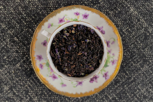 teacup full of black tea and tiny violet flowers