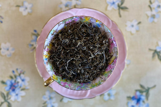teacup full of silver-tipped curly green tea leaves