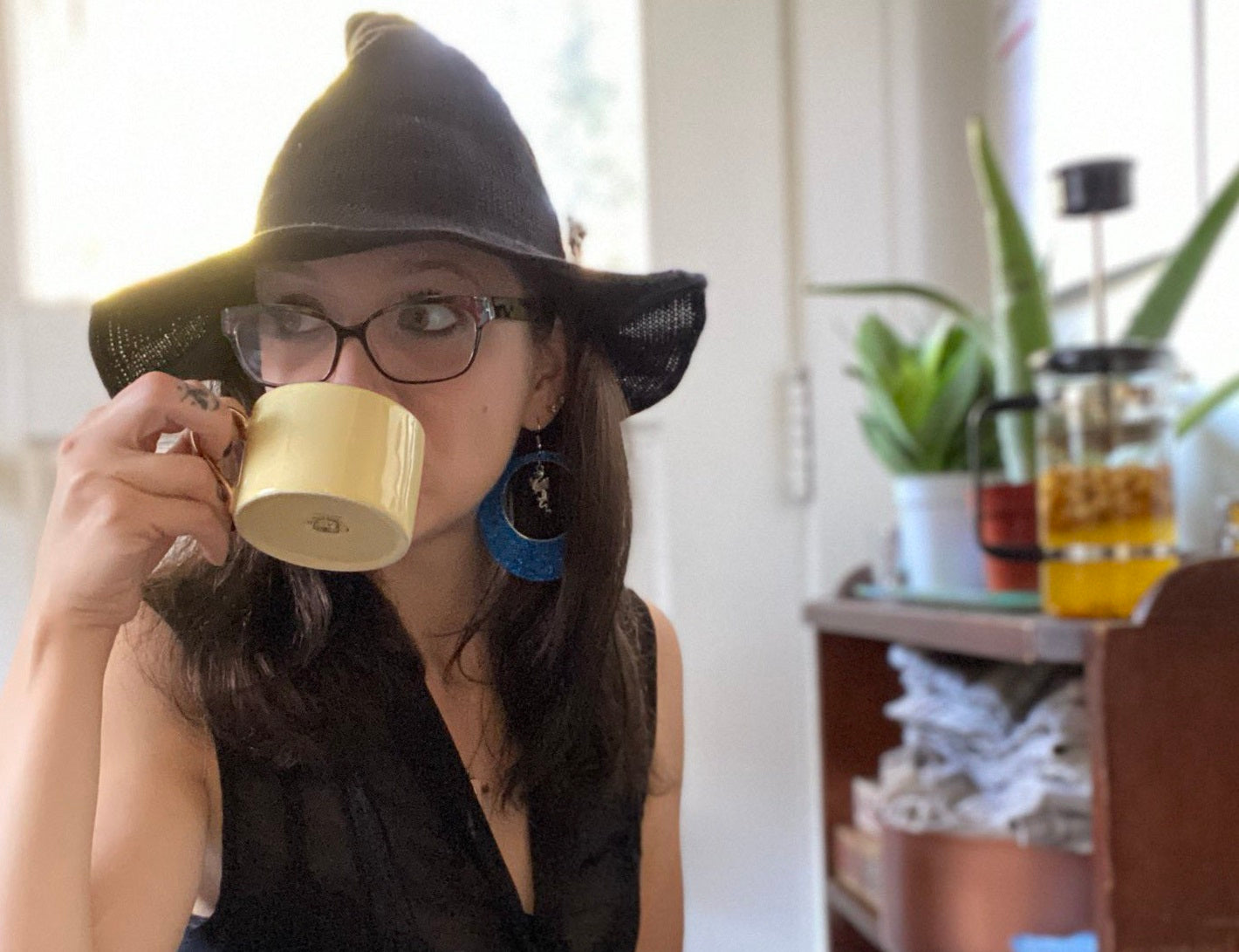 A woman in a witch hat sips tea.