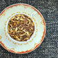 Teacup full of rooibos red tea with orange blossom curls and yellow chips of turmeric