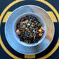 Teacup full of dark tea with apple, blue sprinkles and flowers