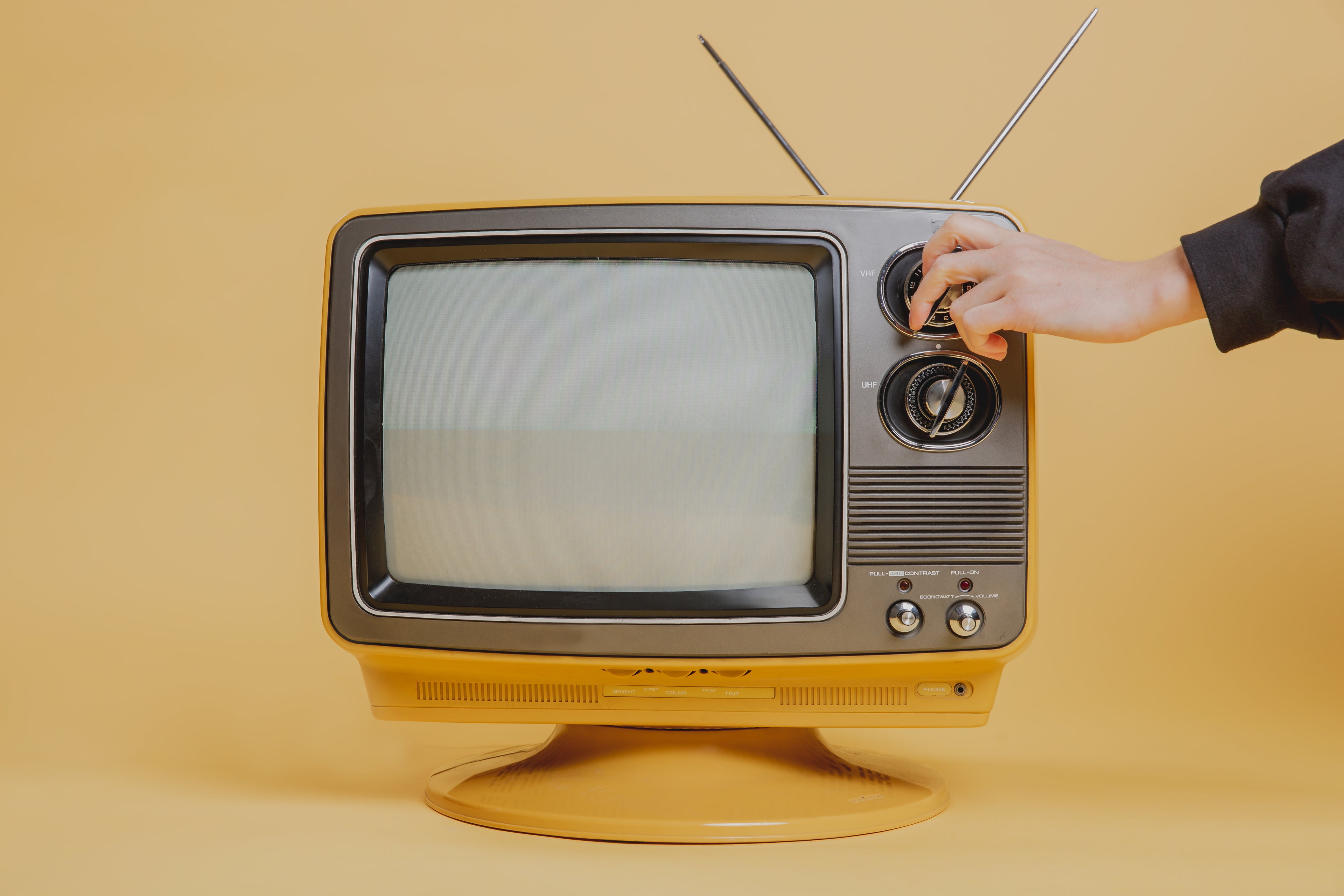 A hand tunes a vintage TV set